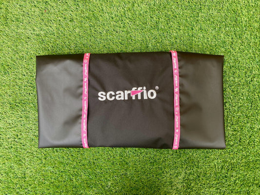 Showing a folded Custom Jet Black and Pink scarffio® on a grass background. The folded scarffio® shows the contrasting Hot Pink embroidered cape and branded edging .
