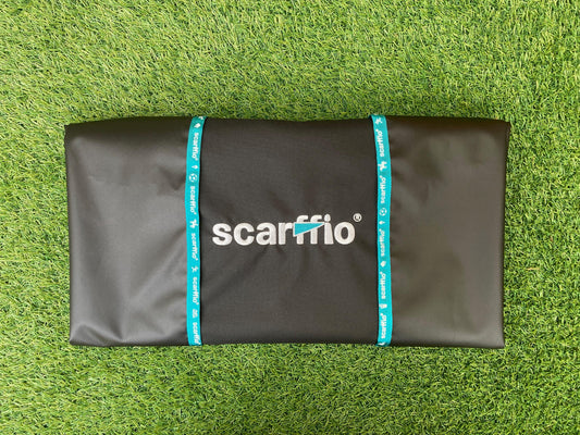Showing a folded Custom Jet Black and Pink scarffio® on a grass back ground. The folded scarffio® shows the contrasting Wild Teal embroidered cape and edging strip.